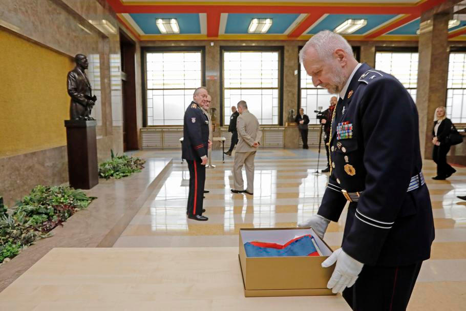 Zástupci prezidentské kanceláře předávají zástupcům armádního muzea téměř 110 let starý český prapor