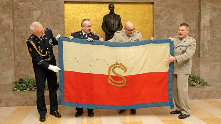Zástupci prezidentské kanceláře předávají zástupcům armádního muzea téměř 110 let starý český prapor