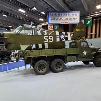 Vojenský nákladní automobil GMC s letadlem v zadní části.