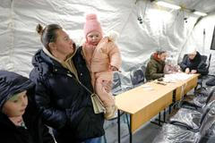 Obyvatelé se zahřívají ve stanu humanitárního centra provozovaného vládou, kde si mohou nabít své elektronické přístroje, dostat teplé jídlo, pití a psychologickou podporu. Stan byl postaven vedle bytových domů během výpadku elektřiny poté, co byla kritická občanská infrastruktura zasažena nedávnými ruskými raketovými a dronovými útoky v rámci ruské invaze na Ukrajinu, Kyjev, Ukrajina, 25. ledna 2026.