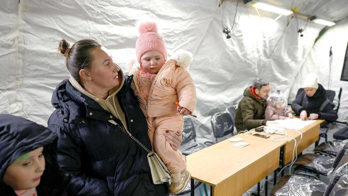 Obyvatelé se zahřívají ve stanu humanitárního centra provozovaného vládou, kde si mohou nabít své elektronické přístroje, dostat teplé jídlo, pití a psychologickou podporu. Stan byl postaven vedle bytových domů během výpadku elektřiny poté, co byla kritická občanská infrastruktura zasažena nedávnými ruskými raketovými a dronovými útoky v rámci ruské invaze na Ukrajinu, Kyjev, Ukrajina, 25. ledna 2026.