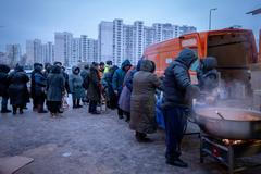 Lidé, kteří po ruských leteckých útocích nemají doma elektřinu, čekají ve frontě na bezplatné teplé jídlo v obytné čtvrti v Kyjevě na Ukrajině.