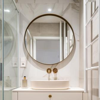 Koupelna, poslední místnost bytu, prošla proměnou, která respektuje její velikost i potřeby obyvatel. Na přání klientů zde vanu nahradil sprchový kout - díky tomu vznikl další úložný prostor. Čisté linie a kvalitní materiály doplňují mosazné baterie a úchytky zásuvek, které působí jako jemné šperky.