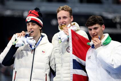 Stříbrný Metoděj Jílek, zlatý  Sander Eitrem a bronzový Riccardo Lorell na stupních vítězů po závodě rychlobruslařů na 5000 m na ZOH 2026