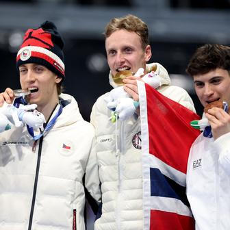 Stříbrný Metoděj Jílek, zlatý  Sander Eitrem a bronzový Riccardo Lorell na stupních vítězů po závodě rychlobruslařů na 5000 m na ZOH 2026