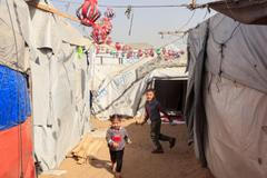Palestinian children play among tents decorated with handmade Ramadan lanterns, in Khan Younis