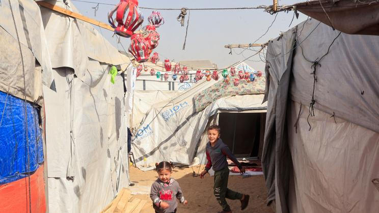 Palestinian children play among tents decorated with handmade Ramadan lanterns, in Khan Younis