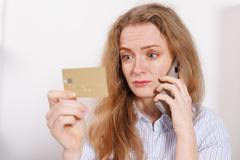 Confused,Woman,With,Credit,Card,Talking,On,Phone,At,Home.