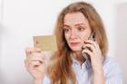 Confused,Woman,With,Credit,Card,Talking,On,Phone,At,Home.