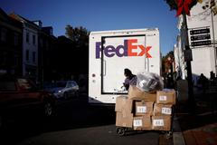 FILE PHOTO: A driver of FedEx stands with packages near a delivery truck during Black Friday preparations in the Georgetown neighborhood of Washington