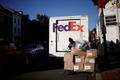 FILE PHOTO: A driver of FedEx stands with packages near a delivery truck during Black Friday preparations in the Georgetown neighborhood of Washington