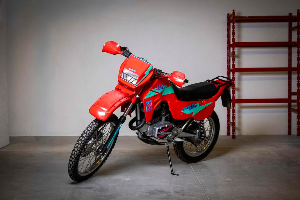 Naprosto unikátní je kolekce šesti nejetých motocyklů ČZ v původním stavu z 90. let, každá s vyvolávací cenou 40 tisíc korun. Toto je lehké cestovní enduro ČZ 180/487 Roland z roku 1994 vyrobené ve spolupráci se slovenskou firmou Moto Yuropa Senec a původně určené na export.