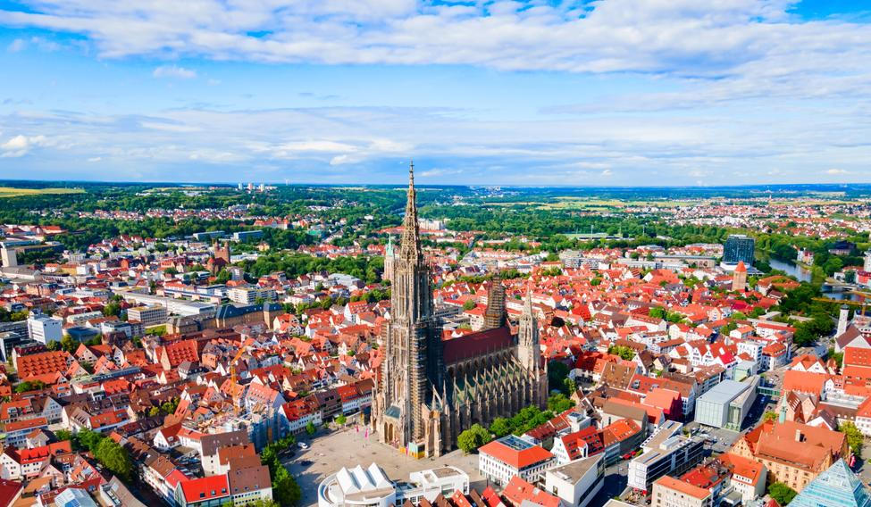 Letecký pohled na Ulm s dominantní katedrálou Ulm Minster, ikonou města známého svou dlouhodobou municipální bytovou politikou.