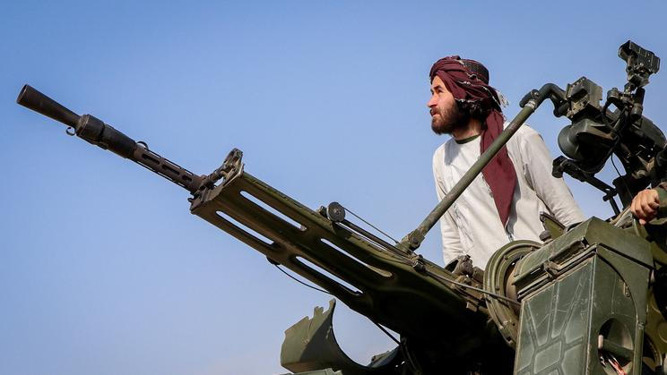A Taliban soldier stands next to an anti-aircraft gun while on lookout for Pakistani fighter jets, in Khost province