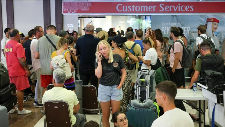 Stranded passengers wait near Emirates Airways customer service office at I Gusti Ngurah Rai International Airport after flights to Doha, Dubai, and Abu Dhabi were cancelled following strikes on Iran launched by the United States and Israel, in Kuta, Bali