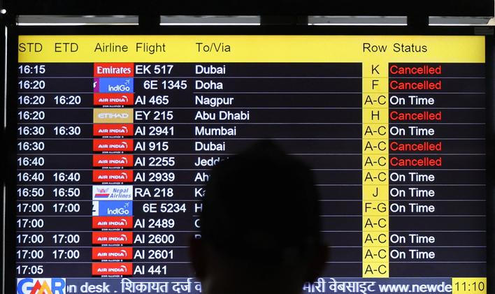 A man views a screen displaying flight information at the Indira Gandhi International airport in New Delhi