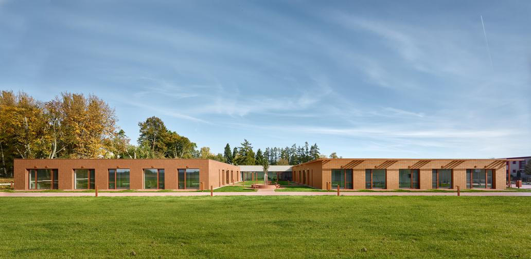 Architekt David Kraus ji navrhl jako klidnou přízemní stavbu, která spíše splývá s okolím, než aby se snažila dominovat prostoru.