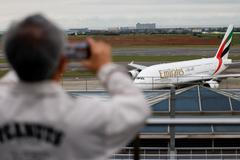 A person takes a photo of an Emirates flight arriving from Dubai as it lands at Taoyuan International Airport in Taoyuan