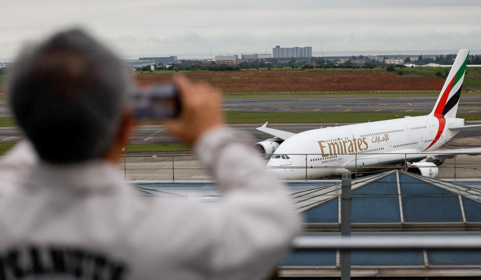 A person takes a photo of an Emirates flight arriving from Dubai as it lands at Taoyuan International Airport in Taoyuan
