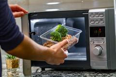 Using,The,Microwave,Oven,To,Heat,Food.,Woman's,Hand,Puts