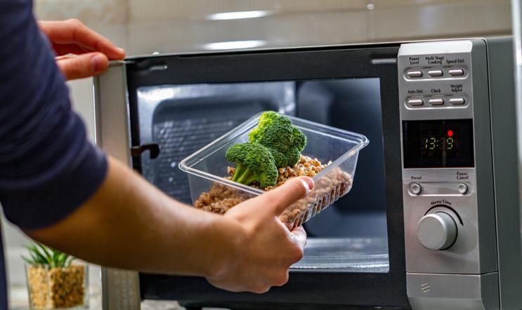 Using,The,Microwave,Oven,To,Heat,Food.,Woman's,Hand,Puts