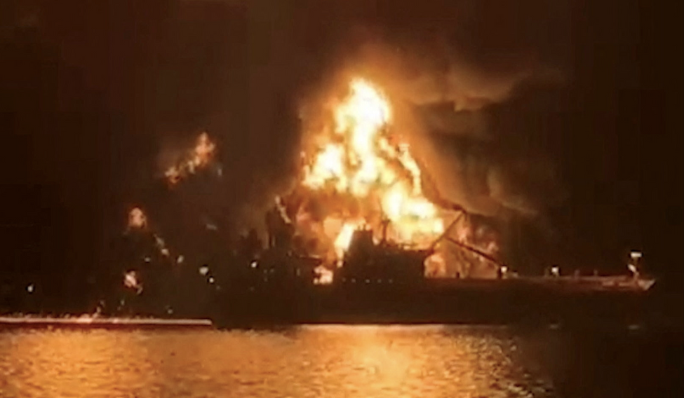 Loď osvětlují plameny z hořícího tankeru poté, co na dva tankery v iráckých vodách zřejmě zaútočily íránské lodě naložené výbušninami.