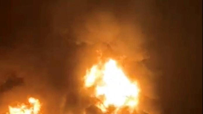 A ship is illuminated by fire from a burning vessel, after Iranian explosive-laden boats appear to have attacked two fuel tankers in Iraqi waters setting them ablaze