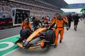 Mechanici McLarenu tlačí monopost Oscara Piastriho do boxů v Šanghaji