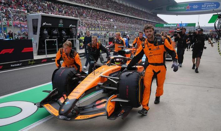 Mechanici McLarenu tlačí monopost Oscara Piastriho do boxů v Šanghaji