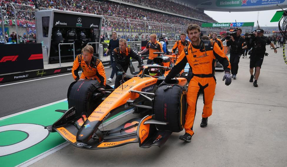 Mechanici McLarenu tlačí monopost Oscara Piastriho do boxů v Šanghaji