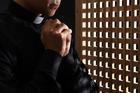 Young,Priest,Praying,In,Confession,Booth,,Closeup