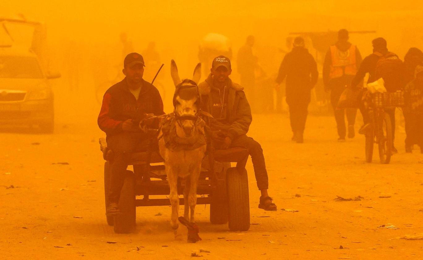 Palestinians displaced during the two-year Israeli offensive shelter in a tent camp, during a sandstorm in Khan Younis 