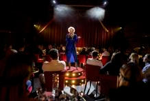 Na pódiu je proto jednou přísnou učitelkou, jindy femme fatale v dlouhých upnutých šatech s rudou rtěnkou a cigaretou, nebo jeptiškou posedlou démony s bičíkem v ruce. V jiném čísle se zase vysvlékne a vstoupí do volně stojící retro vany.