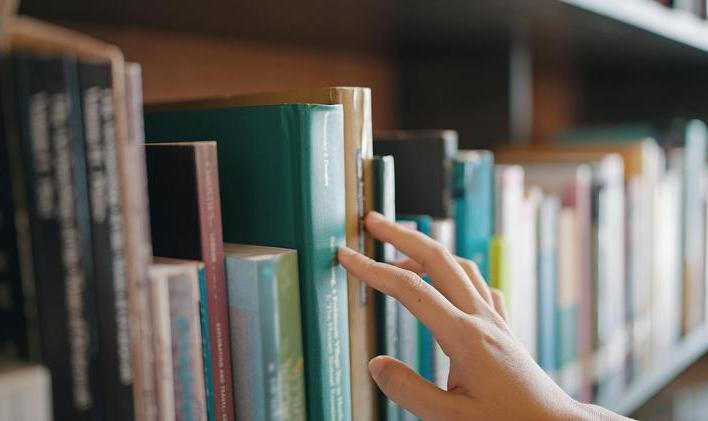 Close,Up,Hand,Search,For,Book,On,Bookshelves,In,The