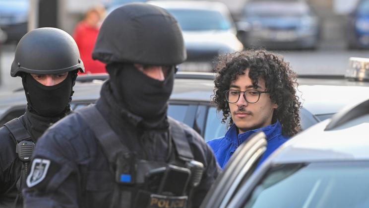 Policisté přivádějí muže v poutech k Okresnímu soudu v Pardubicích v souvislosti s úmyslným zapálením haly zbrojovky LPP Holding, 24. března 2026, Pardubice.