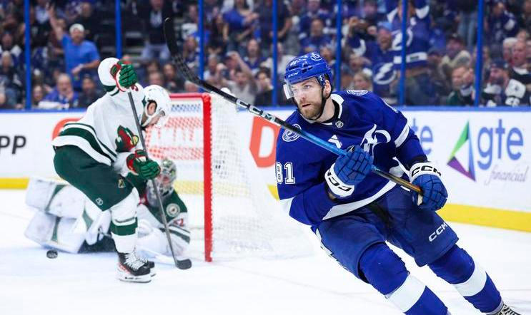 Erik Černák (81) z Tampy Bay slaví gól, zatímco hráči Minnesoty hledí na rozbitou kameru v brance