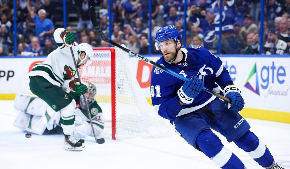 Erik Černák (81) z Tampy Bay slaví gól, zatímco hráči Minnesoty hledí na rozbitou kameru v brance