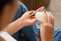 Young,Woman,Taking,Vitamin,Supplements,At,Home,,Closeup