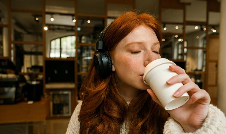 Young,Redhead,Girl,Wearing,Sweater,Listening,Music,With,Headphones,And