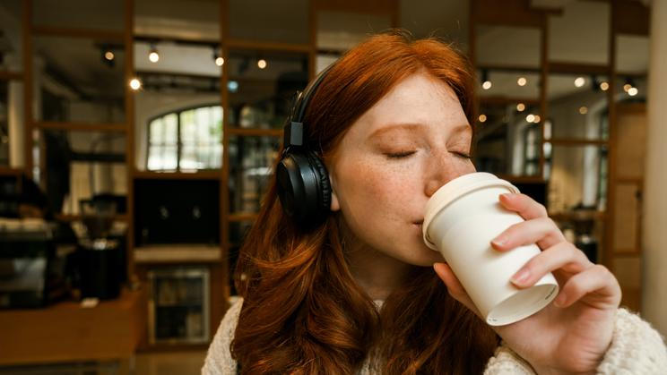 Young,Redhead,Girl,Wearing,Sweater,Listening,Music,With,Headphones,And
