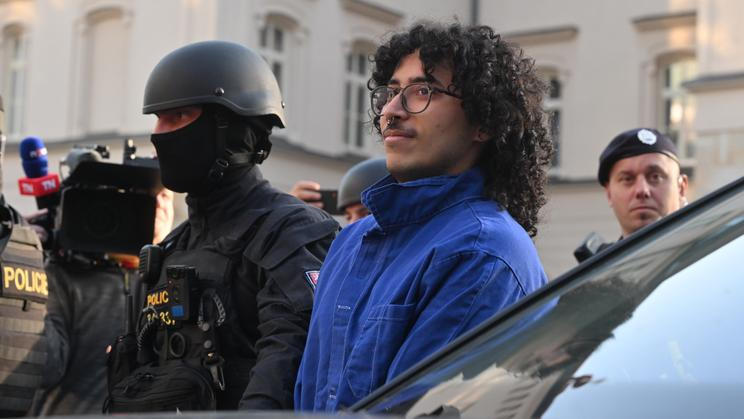 Policisté přivádějí muže v poutech k Okresnímu soudu v Pardubicích, který bude rozhodovat o vazbě pro obviněné z teroristického útoku a účasti na teroristické skupině v souvislosti s úmyslným zapálením haly zbrojovky LPP Holding, 24. března 2026, Pardubice.