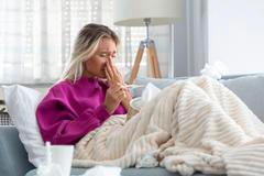 Young Woman Caught Cold Or Flu Illness. Portrait Of Unhealthy Girl blowing her nose