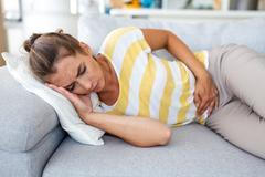 Woman,Lying,On,Sofa,With,Stomach,Pain,And,Nausea.,Abdominal
