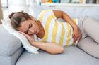 Woman,Lying,On,Sofa,With,Stomach,Pain,And,Nausea.,Abdominal