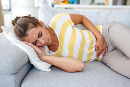 Woman,Lying,On,Sofa,With,Stomach,Pain,And,Nausea.,Abdominal