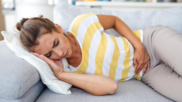 Woman,Lying,On,Sofa,With,Stomach,Pain,And,Nausea.,Abdominal