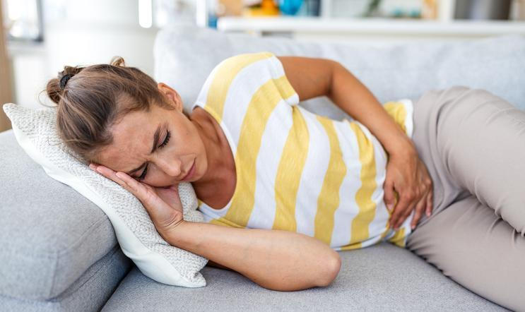 Woman,Lying,On,Sofa,With,Stomach,Pain,And,Nausea.,Abdominal