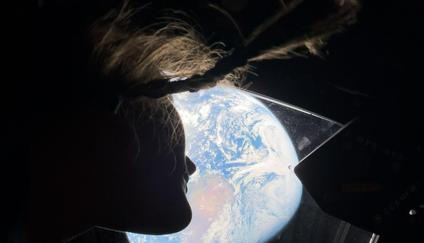 Astronautka mise Artemis II Christina Kochová dívající se kosmické lodi Orion zpět na Zemi, zatímco posádka směřuje k Měsíci.