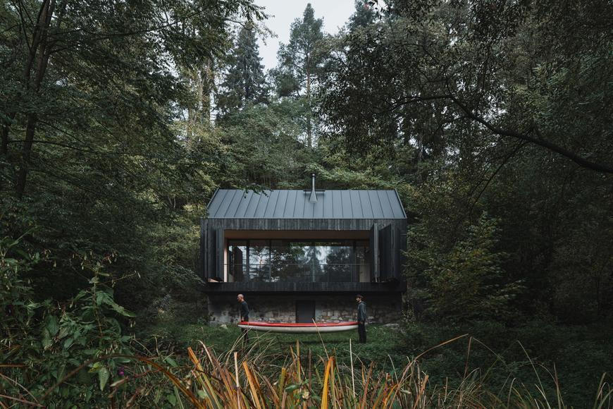 Mezi skálou a řekou. Černá chata povstala z popela a možná překvapivě zapadá do přírody