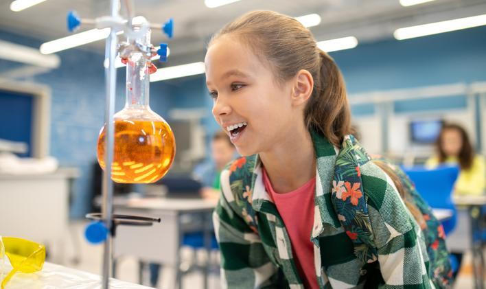 ["Girl with delight looking at flask in chemistry class"]
